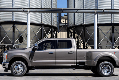 A silver 2024 Ford F-250 Super Duty shown in profile and parked at a commercial site.