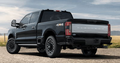 A black 2024 Ford F-250 Platinum shown from the rear and parked on a gravel road.