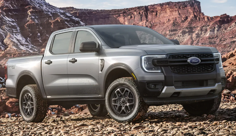 A silver 2024 Ford Ranger parked in a desert, with mountains visible in the background.