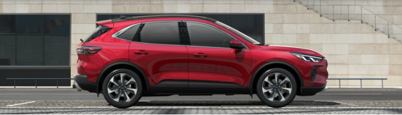 A red 2024 Ford Escape Platinum shown from the side and parked in front of a concrete structure, with a glass building in the background.