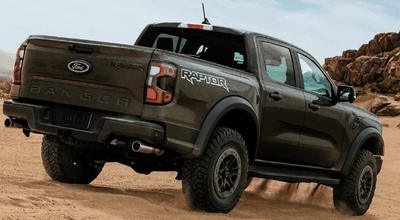 A green 2024 Ford Ranger Raptor shown from the rear as it drives through the desert.