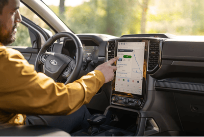 Interior view of the 2024 Ford Ranger Lariat, with a man using the 12-inch touchscreen to control various features.