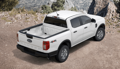 A white 2024 Ford Ranger XL parked on a dirt road and show from the rear, with rocks and shrubs in the background.