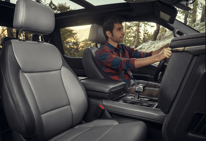 Interior view of the 2024 Ford F-150 Lightning, with a man sitting in the driver seat and the sun visible through the rear passenger window.