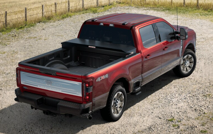 A red 2024 Ford F-350 King Ranch equipped with a Weather Guard toolbox and parked on a gravel road.