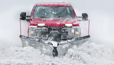 A red 2024 Ford F-350 Super Duty pushing a plow through the snow.