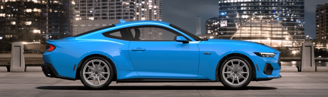 A blue 2024 Ford Mustang GT Premium shown from the side and parked in front of a city-scape.