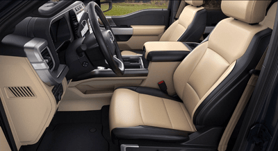 Interior view of the 2024 Ford F-550 Lariat, showing the two-tone leather seats, steering wheel, and storage console.