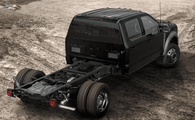 A black 2024 Ford F-550 Lariat chassis cab parked on a dirt road at a work-site.