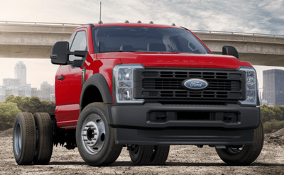 A red 2024 Ford F-550 XL parked at a work-site, with a bridge and city-scape visible in the background.