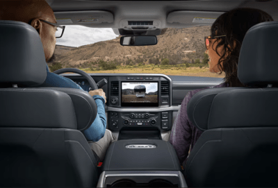 A couple sitting inside the 2023 Ford F-250 Limited and using the 360-degree camera system to view the surrounding environment on the centre stack.