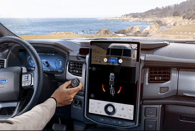 Interior view of the 2024 Ford F-150 Lightning, with the central screen displaying the truck reversal system and a beach visible through the windshield.