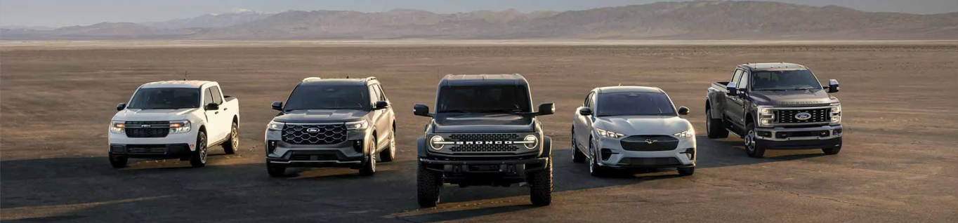 The 2024 Ford line-up - including the Bronco, F-150, and Mustang - parked in a desert, with mountains visible in in the background.