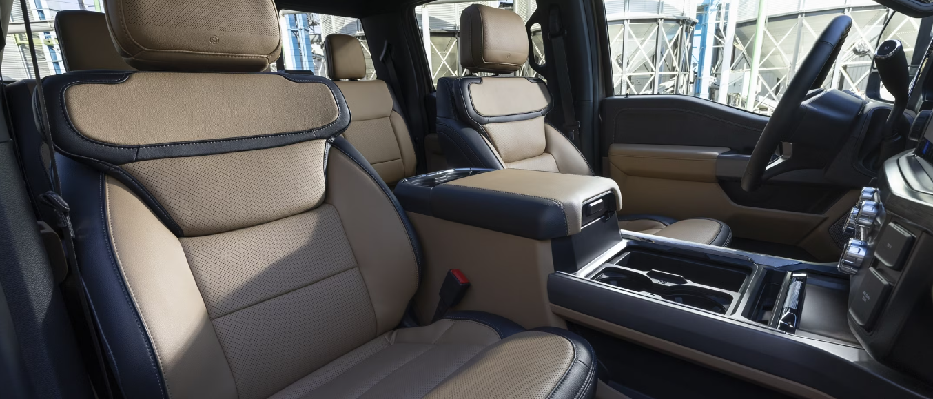 Interior view of a 2023 Ford F-350 Super Duty, showcasing the two-tone leather seats, black steering wheel, and storage console.