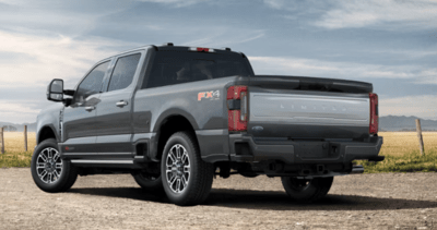 Rear view of a grey 2023 Ford F-350 Limited equipped with the FX4 Package and shown parked on a gravel road.