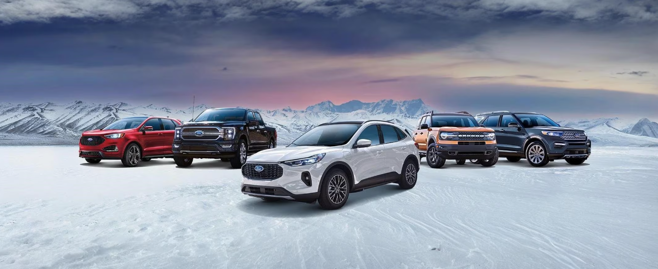 The 2024 Ford vehicle line-up - including the Bronco, Escape, and Expedition - parked on a snowy road, with mountains and grey skies in the background.