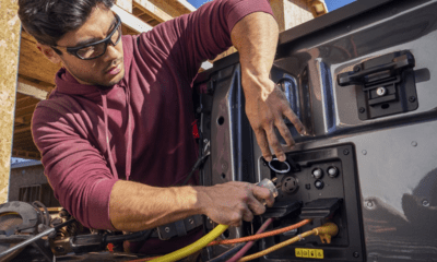 A man leaning into the bed of the 2023 Ford F-150 Lightning and connecting a plug to an integrated outlet.