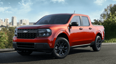 A red 2024 Ford Maverick XLT parked on a cliff, overlooking a cityscape and trees.