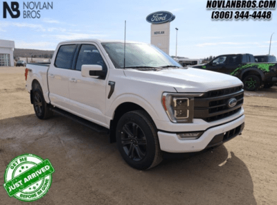 A white 2023 Ford F-150 Lariat parked at the Novlan Bros dealership in Saskatchewan.