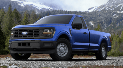 A blue 2024 Ford F-150 XL posed in front of a forest, with snow-capped mountains in the background.