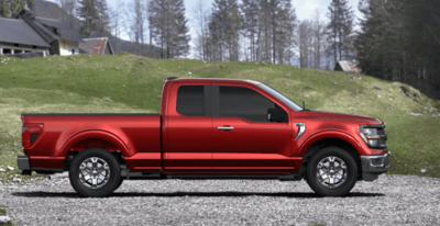 A red 2024 Ford F-150 XLT parked on a gravel driveway, with a hill and white house seen in the background.