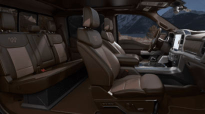 Interior view of the 2023 Ford F-150 King Ranch, with leather seats and wood-grain trim on display.