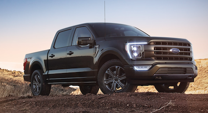 A black 2023 Ford F-150 Lariat Sport parked on a dirt hill at dusk.