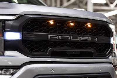 Close-up of a 2022 F-150 with a ROUSH grille, as well as clearance headlights and chrome trim.